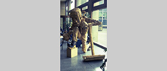 Title: Keverne Late for Work. Sited in the foyer of Leeds Polytechnic building. Wood sculpture 1981